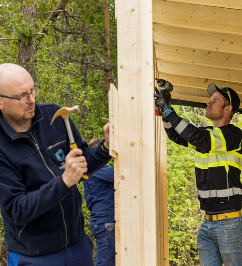 Two men working on building a storage shed